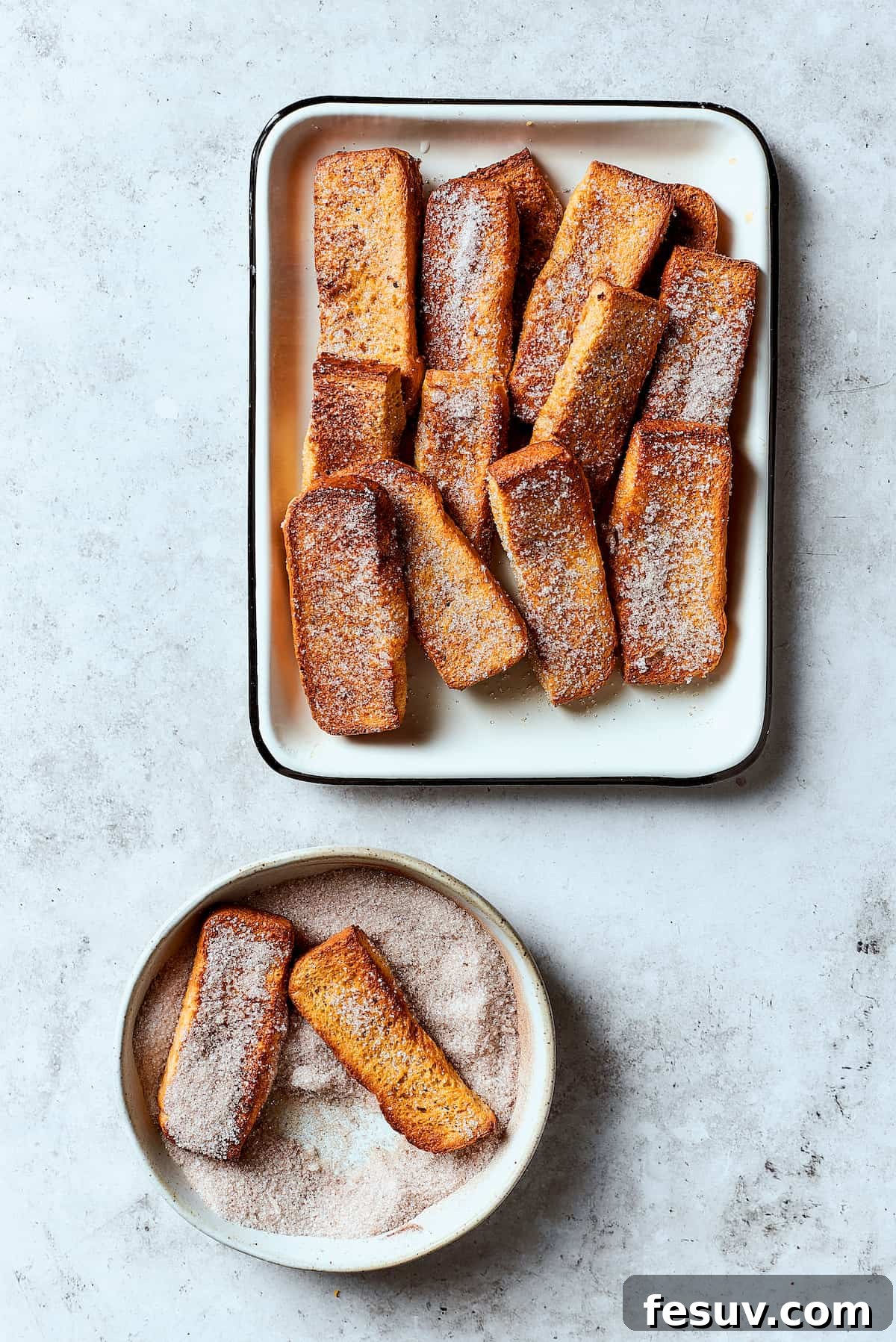 Rolling French toast sticks in cinnamon sugar.