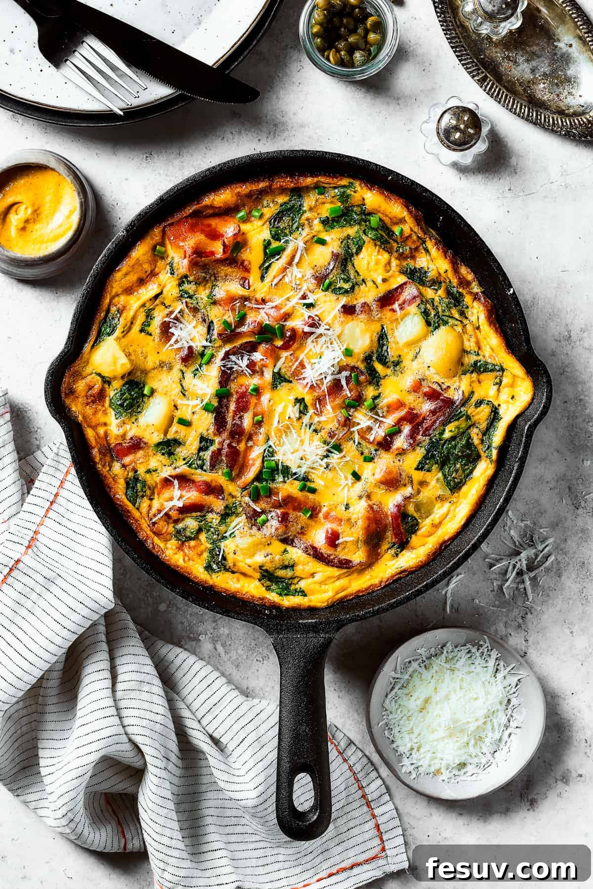 Spinach, Bacon, and Potato Frittata is a healthy, farmhouse-style dinner that's easy to make, and loaded with rich flavor. Perfect easy meal! A fully-cooked frittata in a cast-iron skillet.