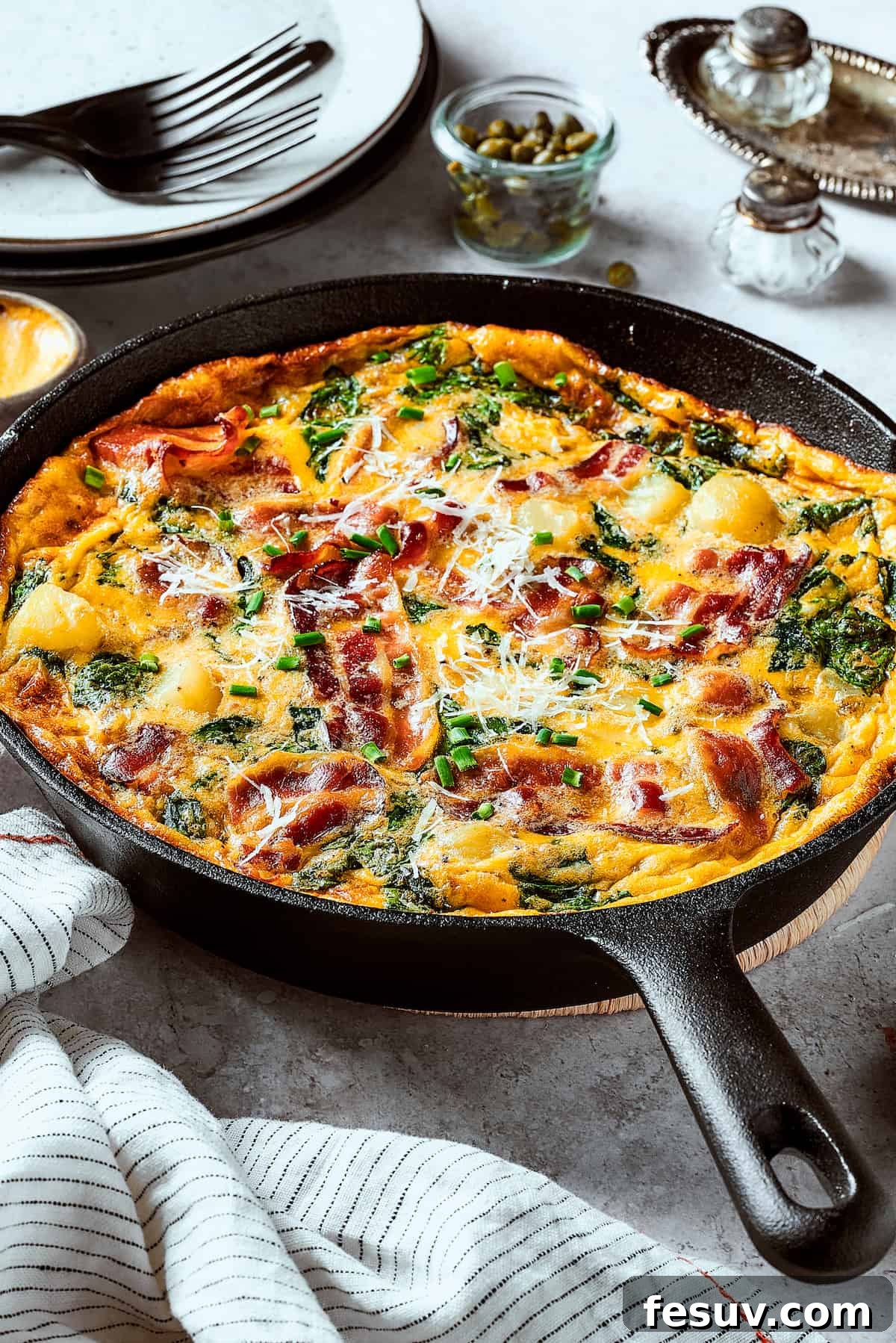 Spinach, Bacon, and Potato Frittata is a healthy, farmhouse-style dinner that's easy to make, and loaded with rich flavor. Perfect easy meal! A cast-iron skillet with a baked egg dish in it.