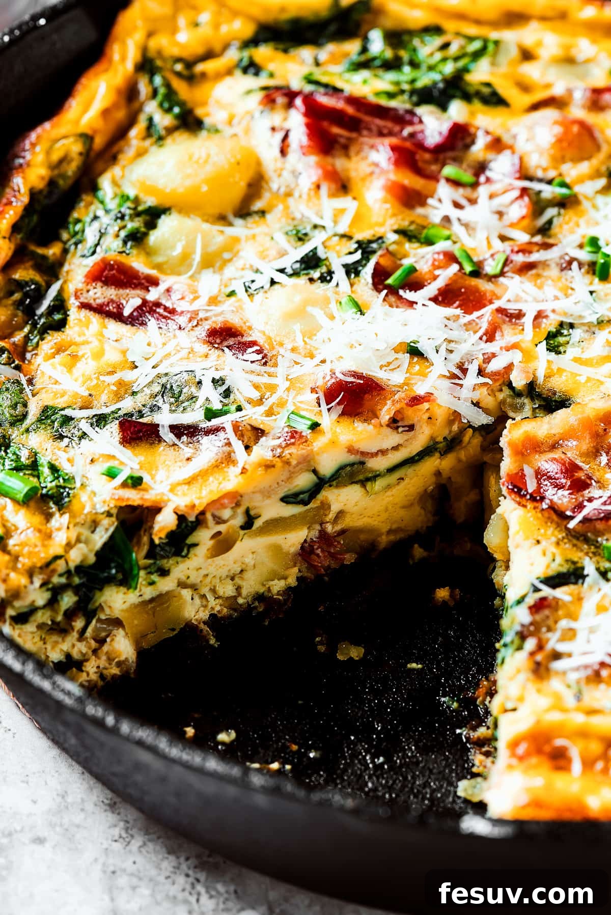 Spinach, Bacon, and Potato Frittata is a healthy, farmhouse-style dinner that's easy to make, and loaded with rich flavor. Perfect easy meal! A baked frittata with a slice removed.