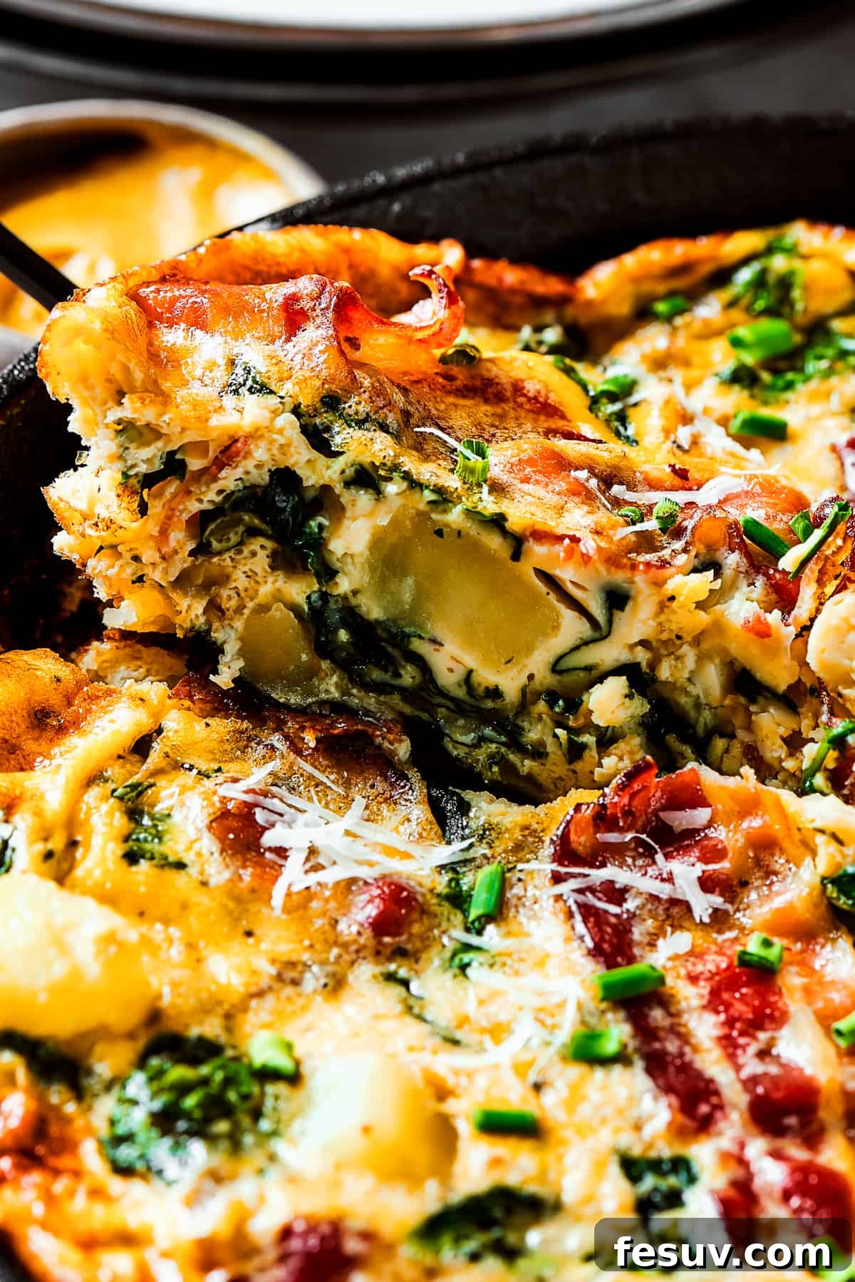 Spinach, Bacon, and Potato Frittata is a healthy, farmhouse-style dinner that's easy to make, and loaded with rich flavor. Perfect easy meal! Lifting a slice of frittata out of a pan.