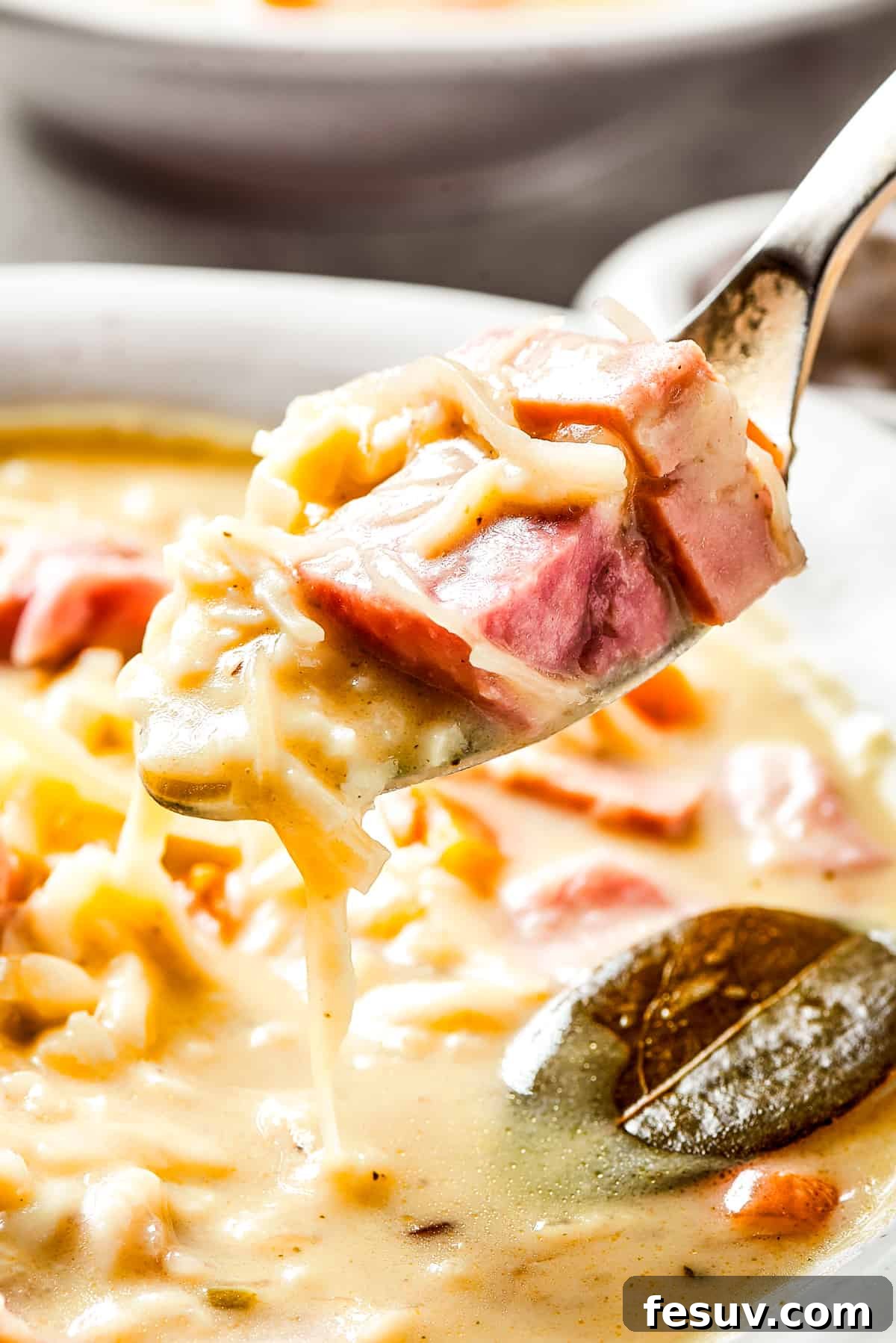 This Creamy Reuben Soup takes corned beef, sauerkraut, and Swiss to a whole new level! It's a comfy, cozy masterpiece in a bowl. Lifting reuben soup out of a bowl with a spoon.