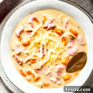 A bowl of creamy soup with a bay leaf in it.