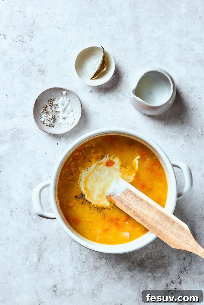 This Creamy Reuben Soup takes corned beef, sauerkraut, and Swiss to a whole new level! It's a comfy, cozy masterpiece in a bowl. Stirring half-and-half into a pot of soup.