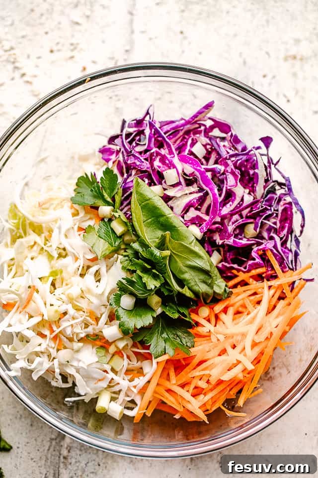 Zesty Asian Cabbage Crunch 3 shredded red and green cabbage in a glass bowl with shredded carrots and fresh cilantro.