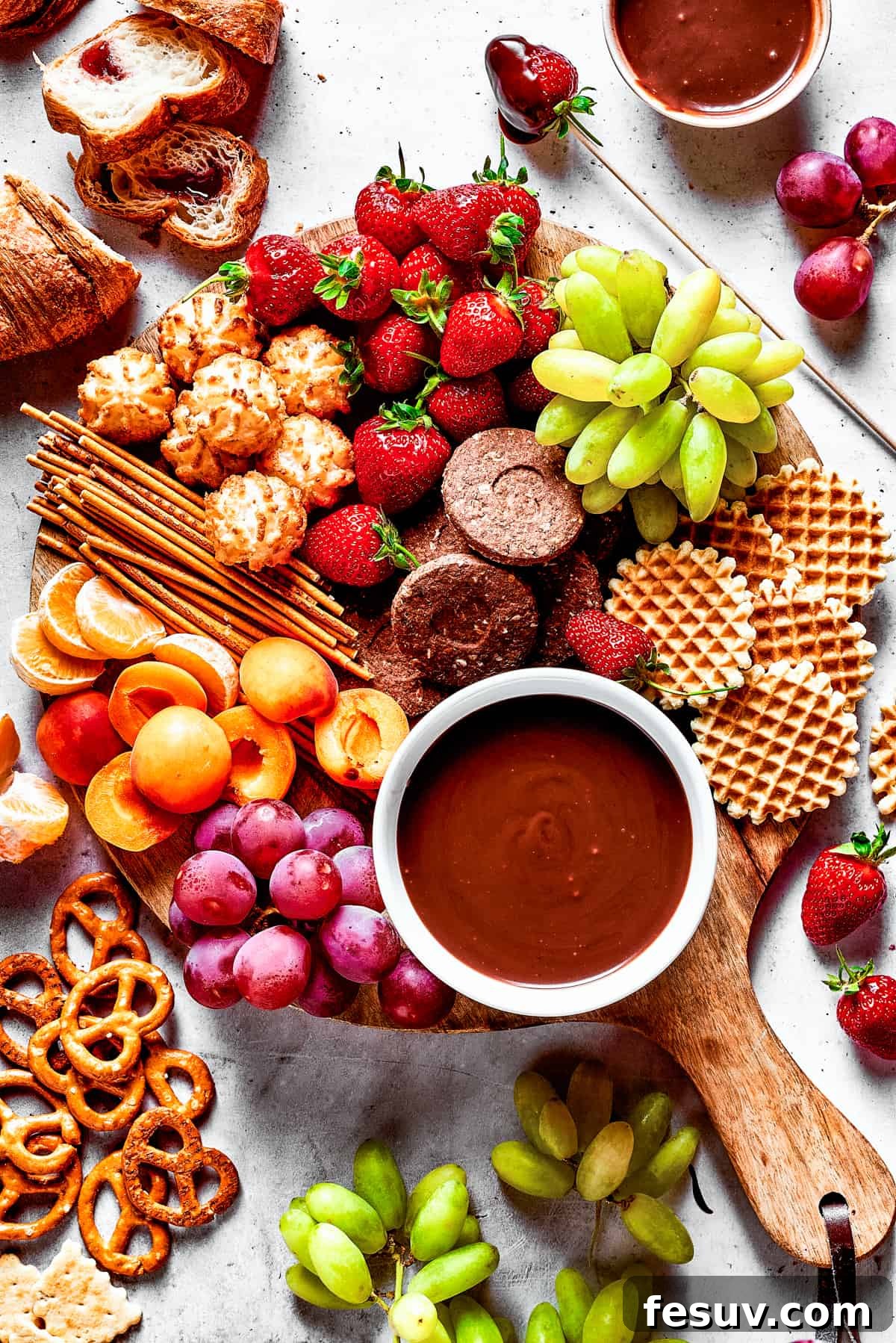 Velvet Chocolate Fondue 3 A dessert board with fruit, waffles, pretzels, and with a bowl of fondue in the center.