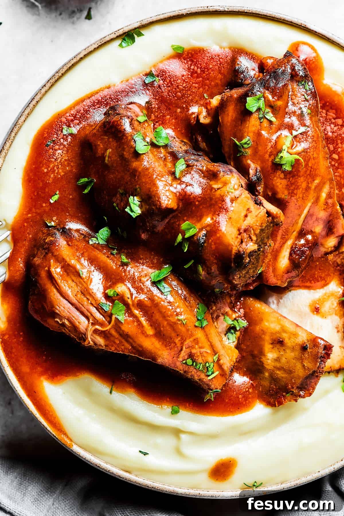 Instant Pot Short Ribs with balsamic sauce are easy to make and so good. Using the Instant Pot gives you irresistibly tender short ribs. Close-up of tender Instant Pot short ribs generously topped with a rich, dark sauce and artfully arranged atop a bed of creamy mashed potatoes, ready to be enjoyed.