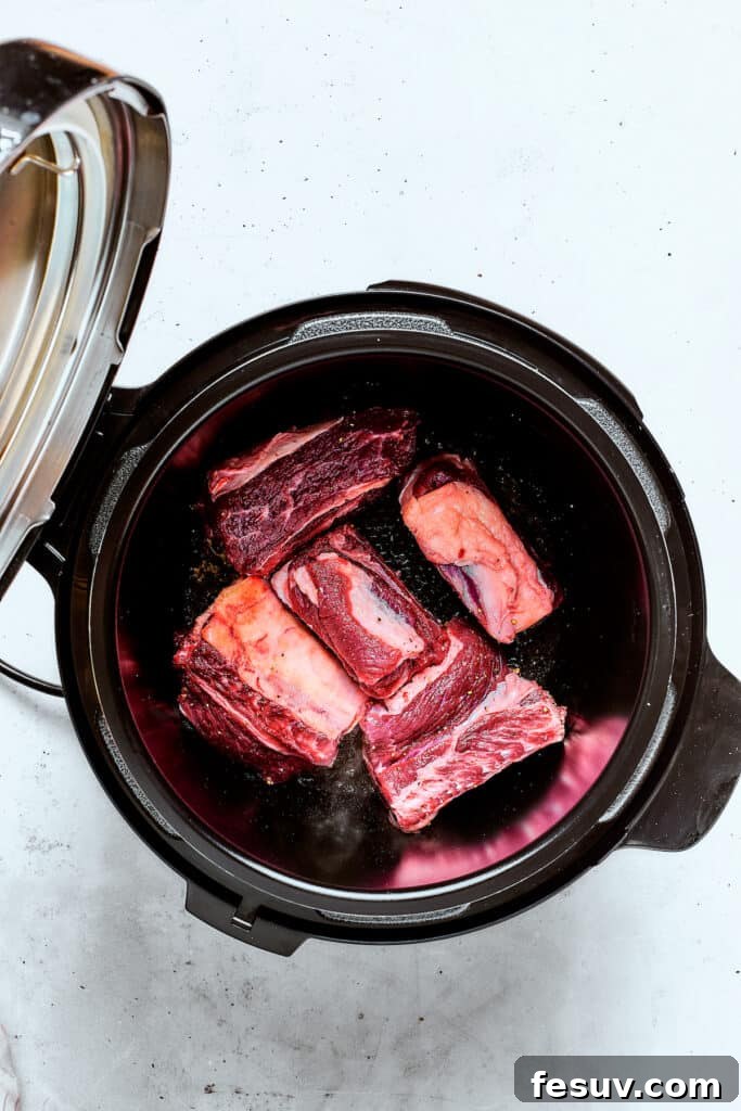 Instant Pot Short Ribs with balsamic sauce are easy to make and so good. Using the Instant Pot gives you irresistibly tender short ribs. Raw short ribs placed carefully in an Instant Pot, ready for searing.