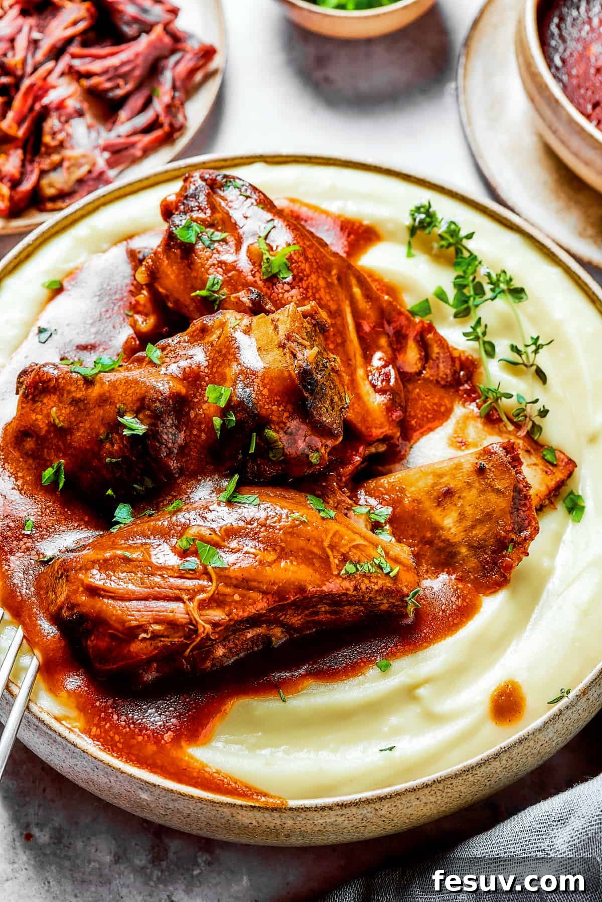 Instant Pot Short Ribs with balsamic sauce are easy to make and so good. Using the Instant Pot gives you irresistibly tender short ribs. Succulent short ribs served over a bed of fluffy mashed potatoes, with additional ribs and a bowl of rich sauce invitingly displayed in the background.