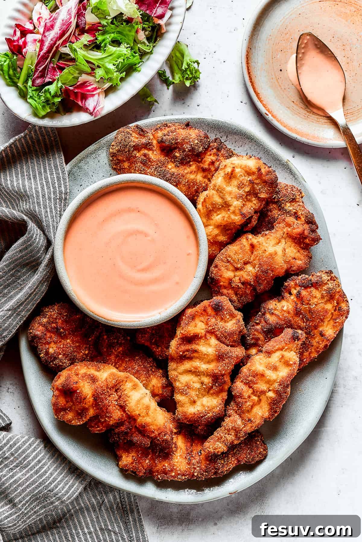 A platter of chicken strips with sauce.