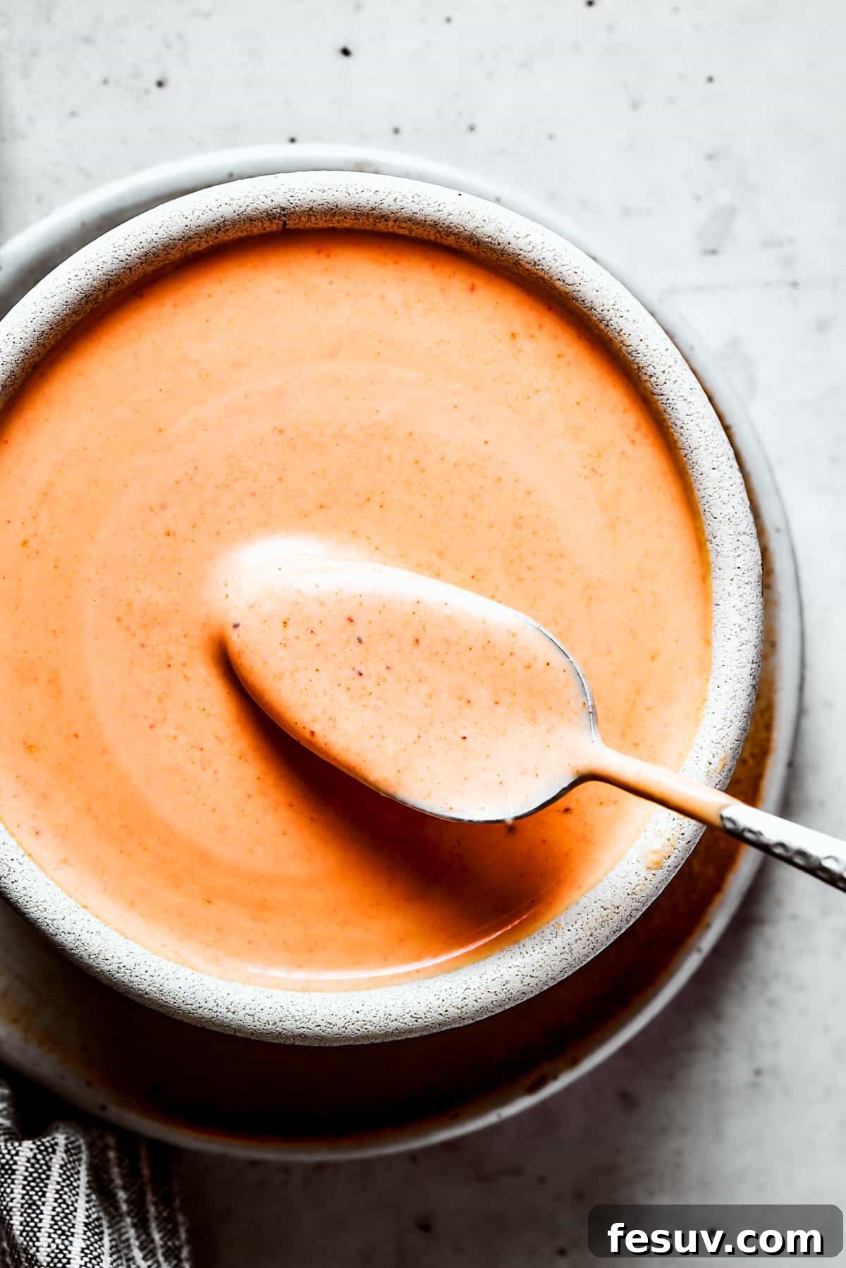 Photo of homemade yum yum sauce in a bowl, with a spoon inside.