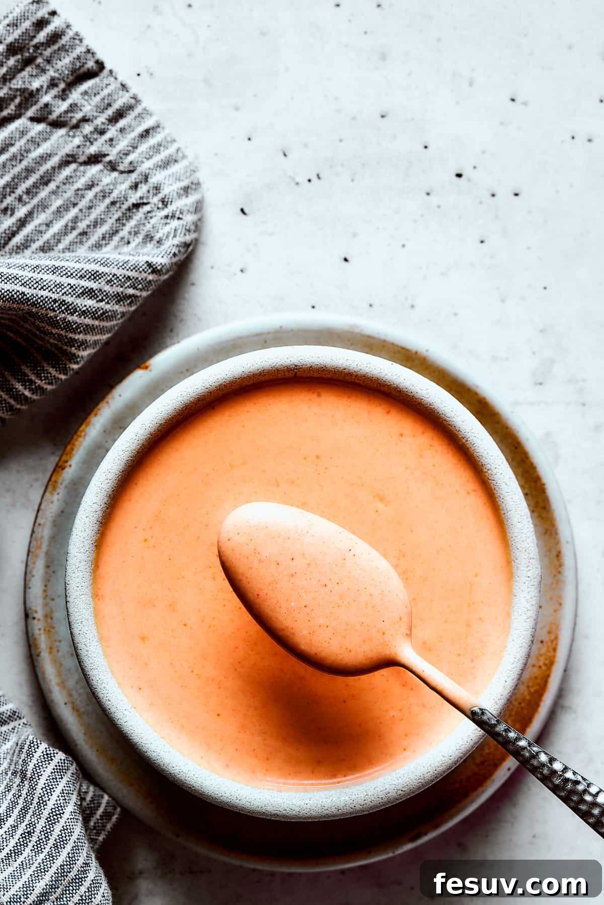 Lifting a spoonful of sauce toward the camera.