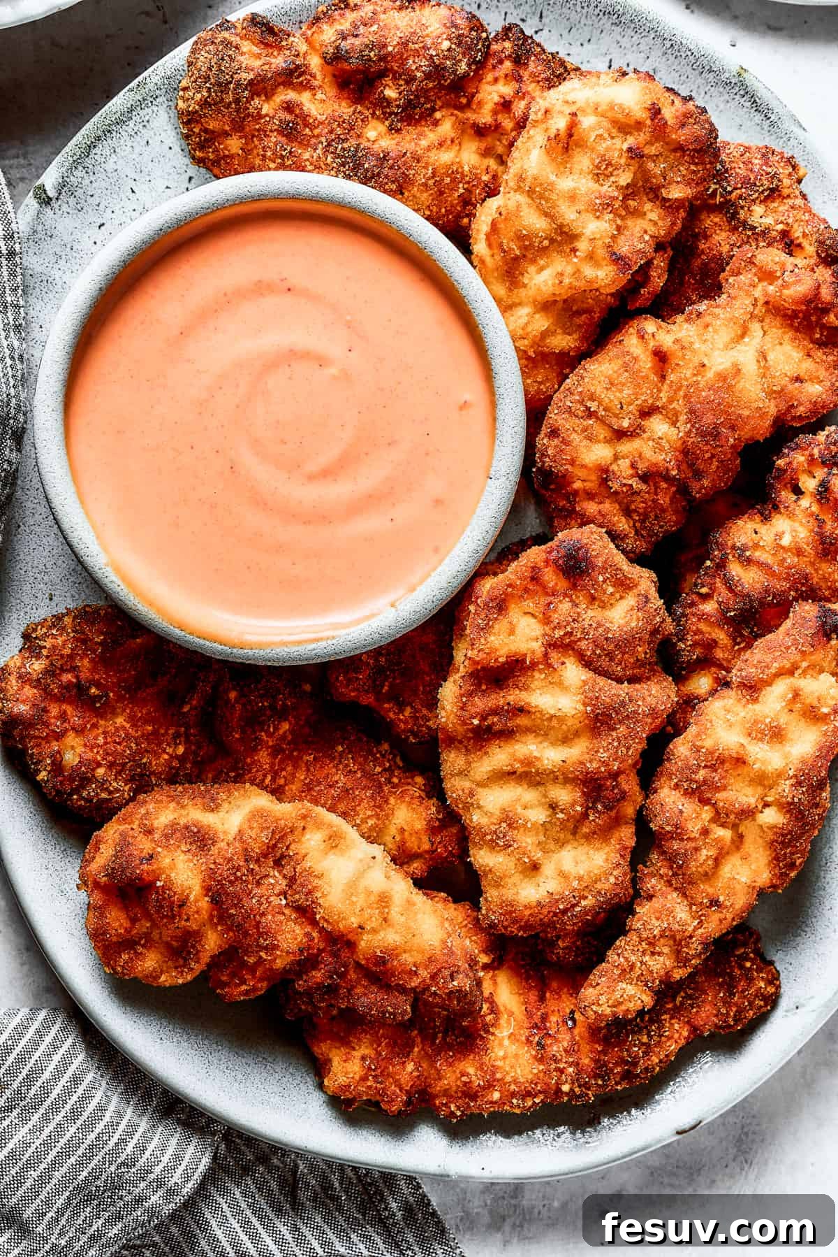 A platter of chicken strips with sauce.