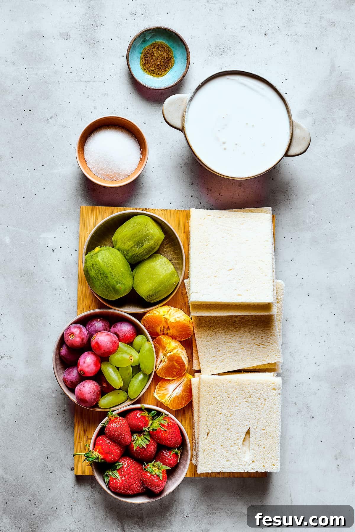 Ingredients for homemade fruit sando measured and arranged on a work surface, including bread, cream, sugar, vanilla, and various fruits.