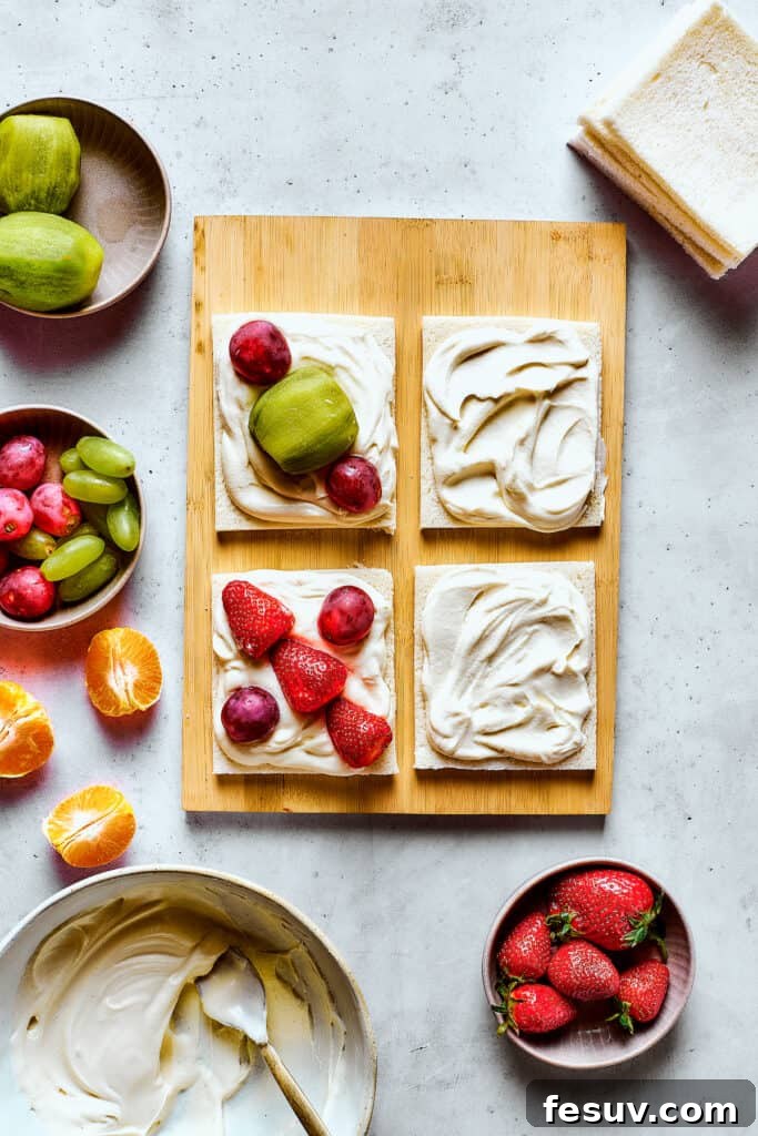 Arranging colorful fruit pieces on a slice of bread with a layer of whipped cream.
