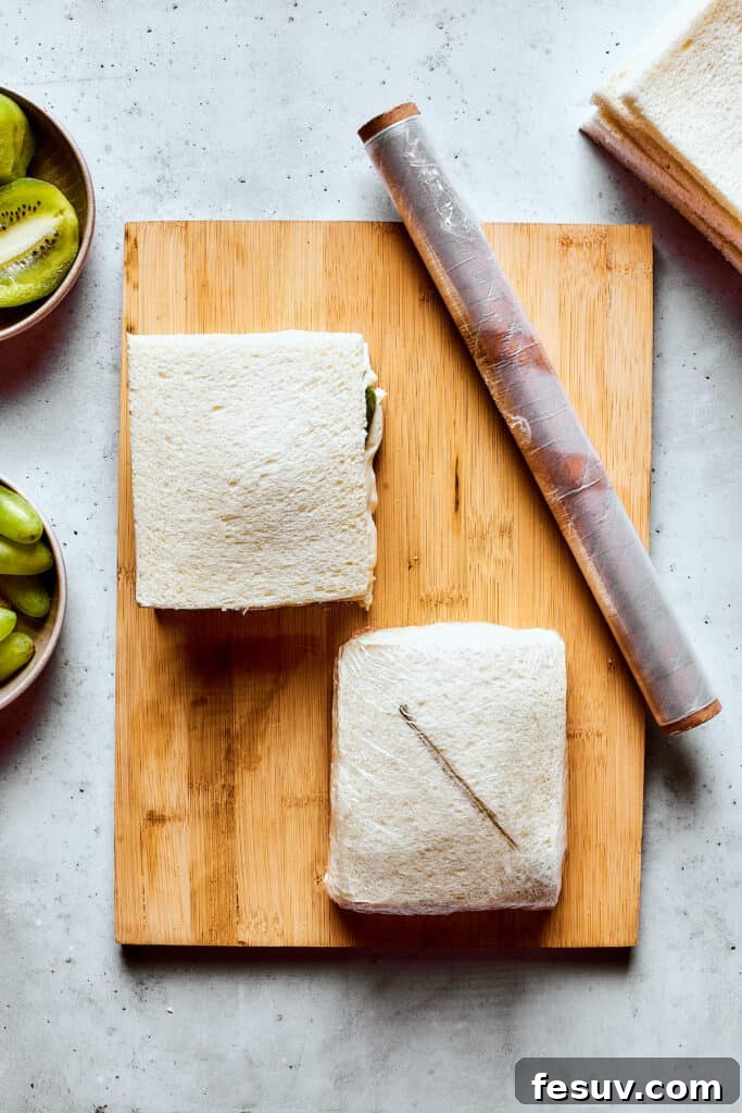 Wrapping individual fruit sandwiches tightly in plastic wrap.