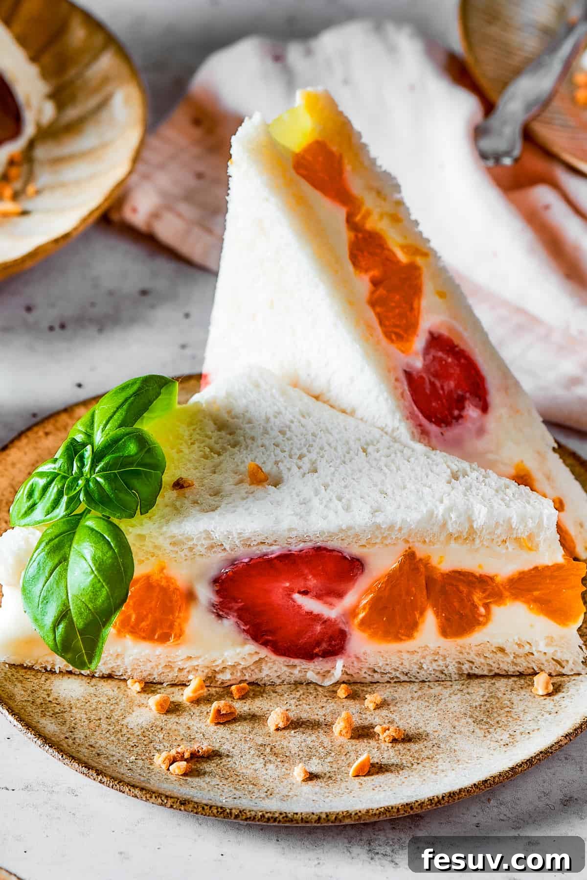 A beautifully prepared sandwich with white bread, mandarin oranges, and strawberries, showcasing the vibrant colors.