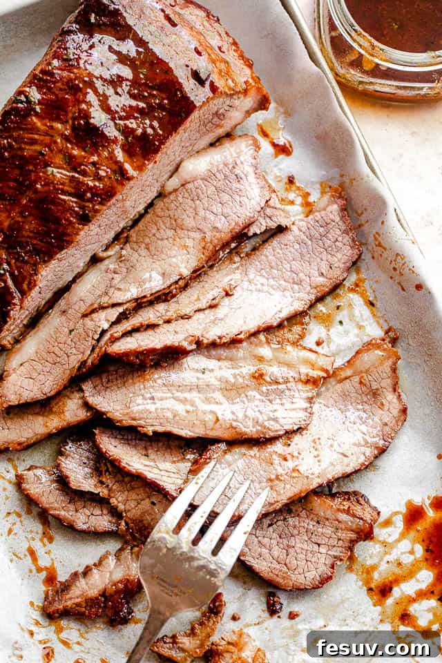 top view of sliced beef brisket with a silver fork placed at the bottom slice and a jar with barbecue sauce to the side