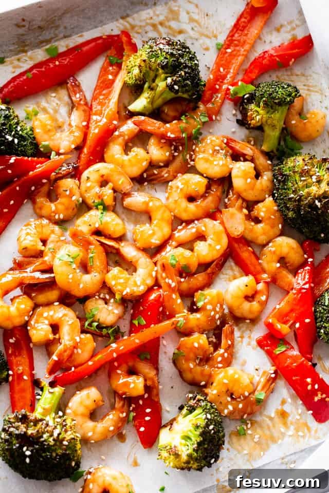 Enjoy a quick, flavorful meal with this sheet pan teriyaki shrimp stir fry, combining tangy sauce, crunchy veggies, and succulent shrimp. Overhead photo of a baking sheet with cooked shrimp, broccoli, and red bell peppers, perfectly roasted.