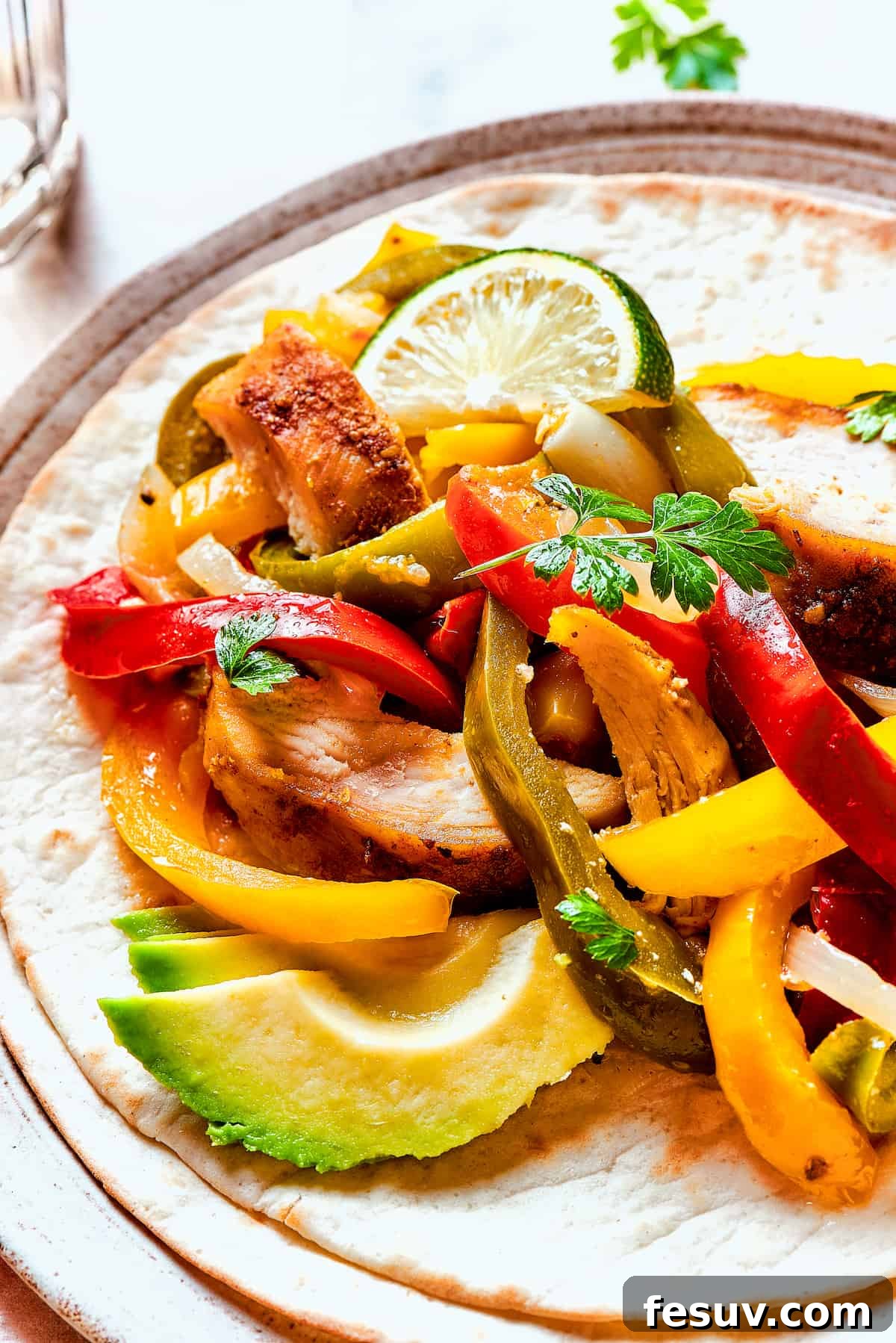 Close-up shot of warm tortillas generously filled with savory fajita chicken, onions, and bell peppers.