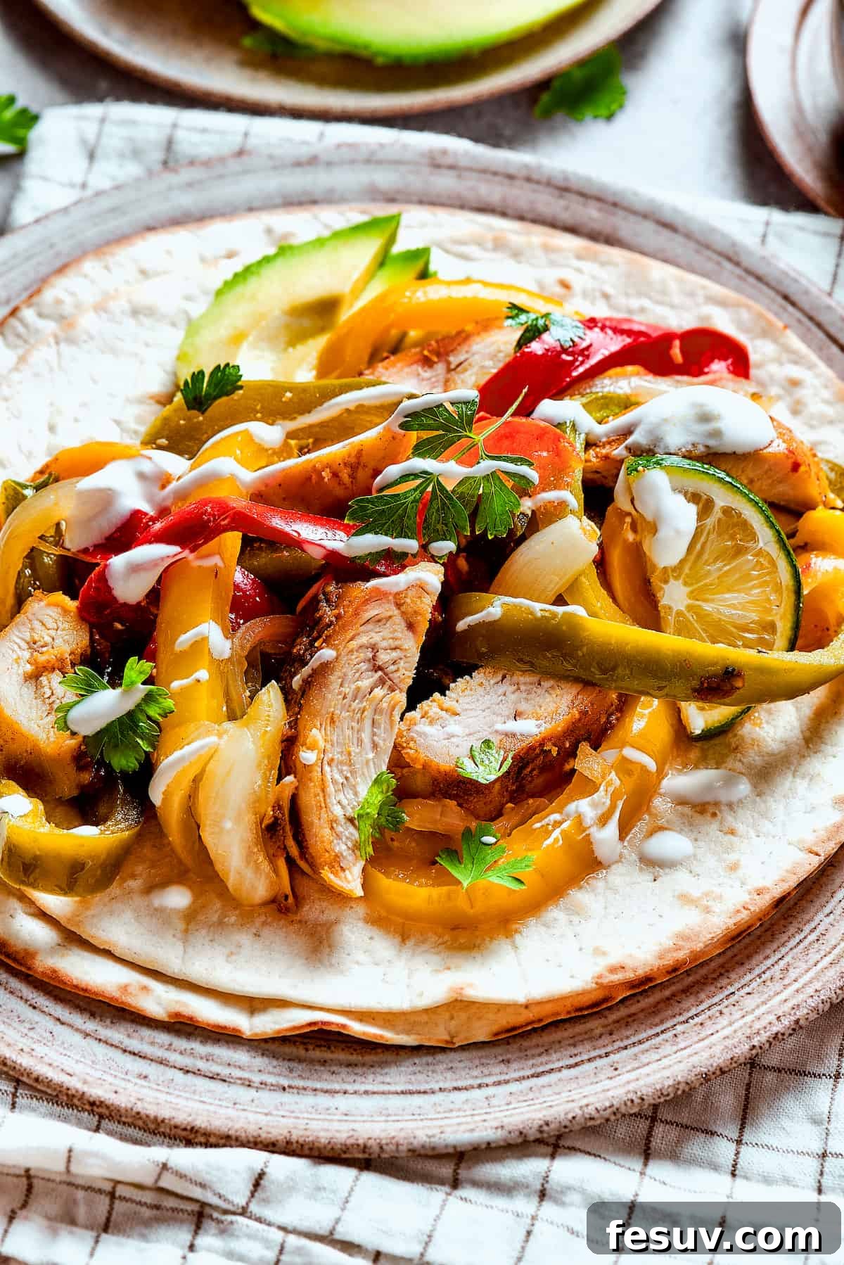 Beautifully arranged homemade chicken fajitas with colorful vegetables, fresh lime slices, and a dollop of sour cream.