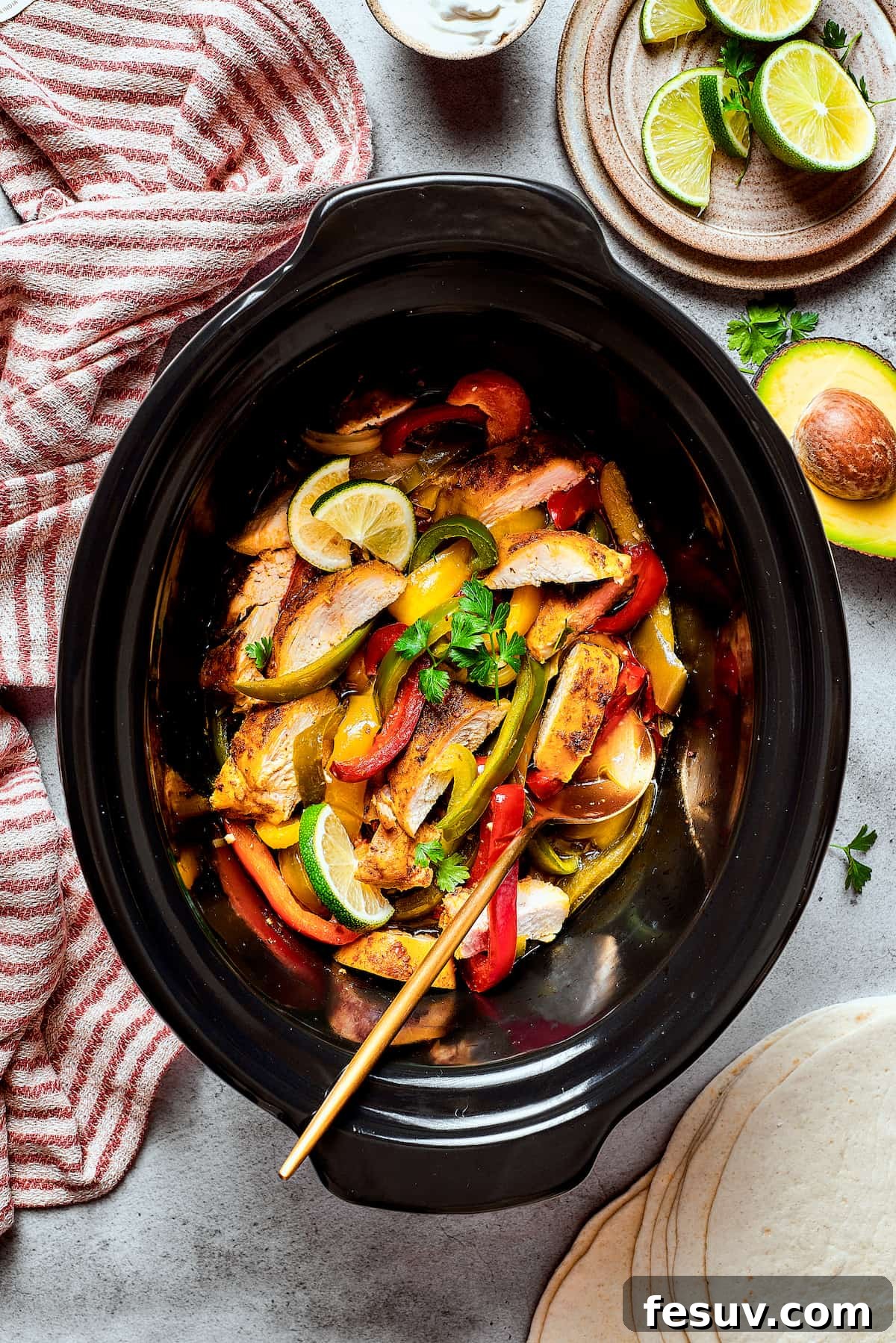 A slow cooker filled with tender, Southwest-style chicken, colorful bell peppers, and onions, ready for serving.