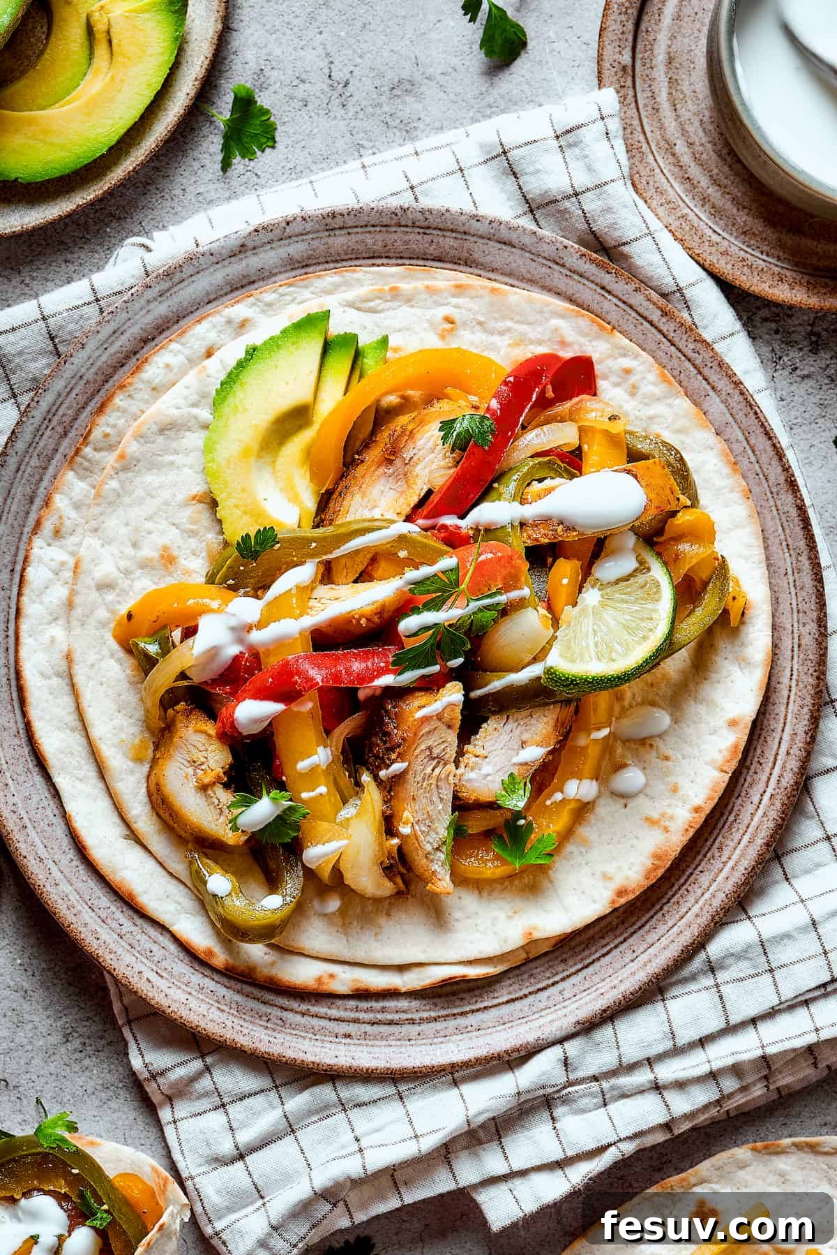Plated Crockpot Chicken Fajitas generously topped with fresh lime, creamy avocado, and a dollop of sour cream.