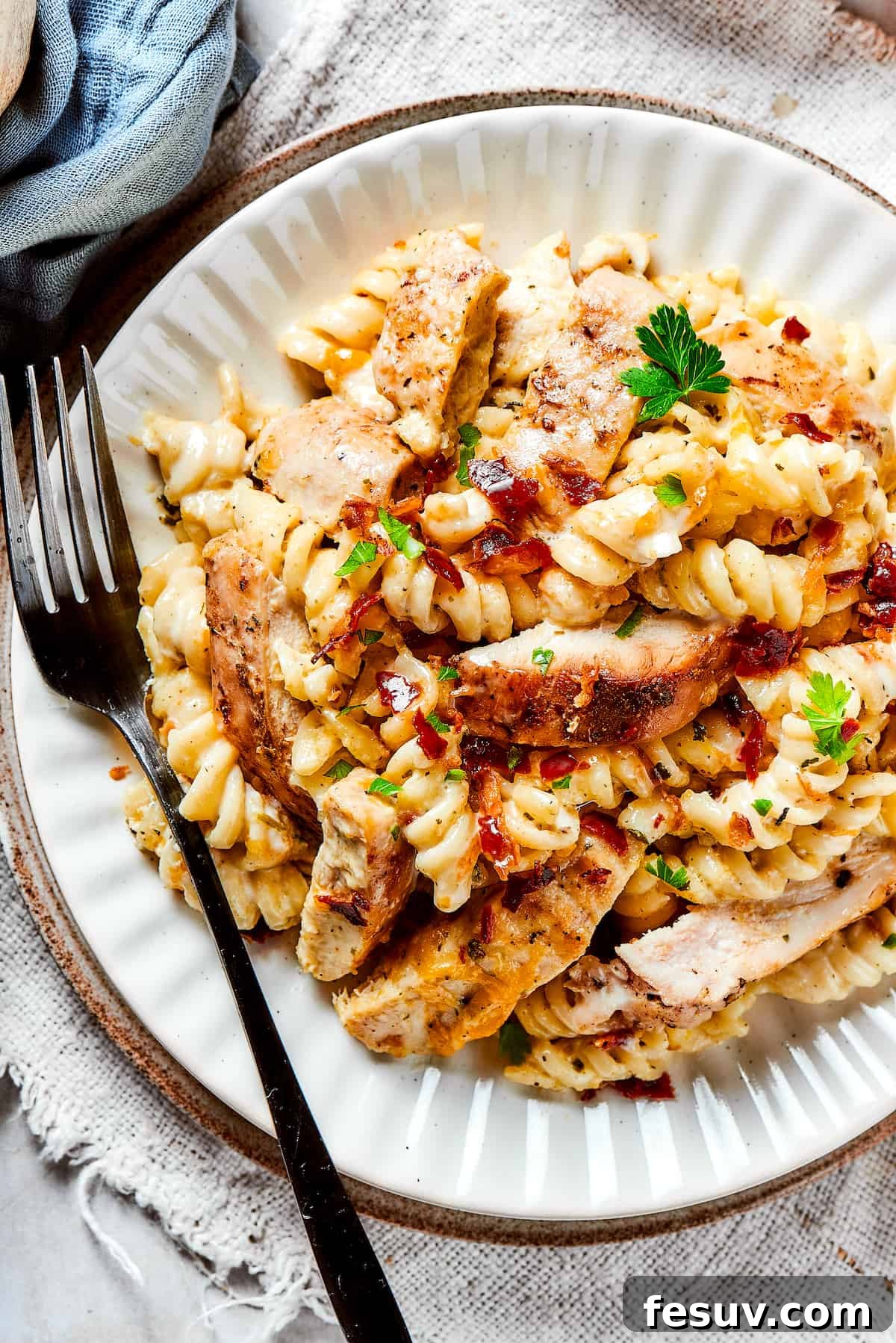 Bold and Creamy Chicken Bacon Ranch Pasta: The Ultimate Comfort Food Dinner! A dinner plate of pasta and chicken with creamy sauce and bacon, garnished with fresh parsley.