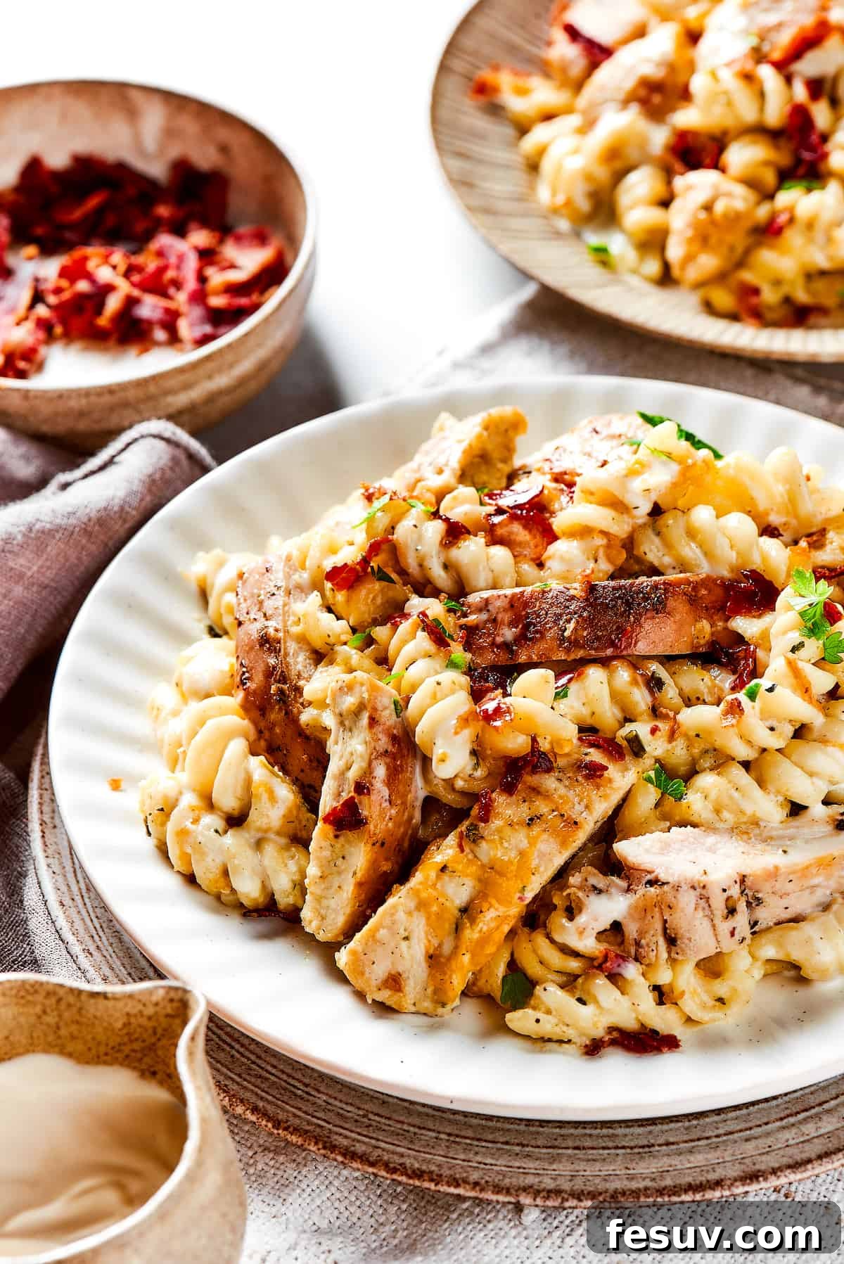 Hearty and Cozy Chicken Bacon Ranch Pasta for a Perfect Family Dinner! Two plates of creamy chicken bacon ranch pasta, garnished with fresh herbs, ready to be served.