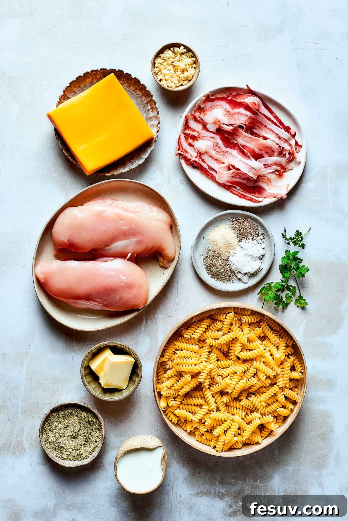 Fresh Ingredients for a Satisfying Chicken Bacon Ranch Pasta Dish! Ingredients for chicken bacon ranch pasta, including pasta, chicken, bacon, cheese, half-and-half, and seasonings, neatly arranged on a work surface.