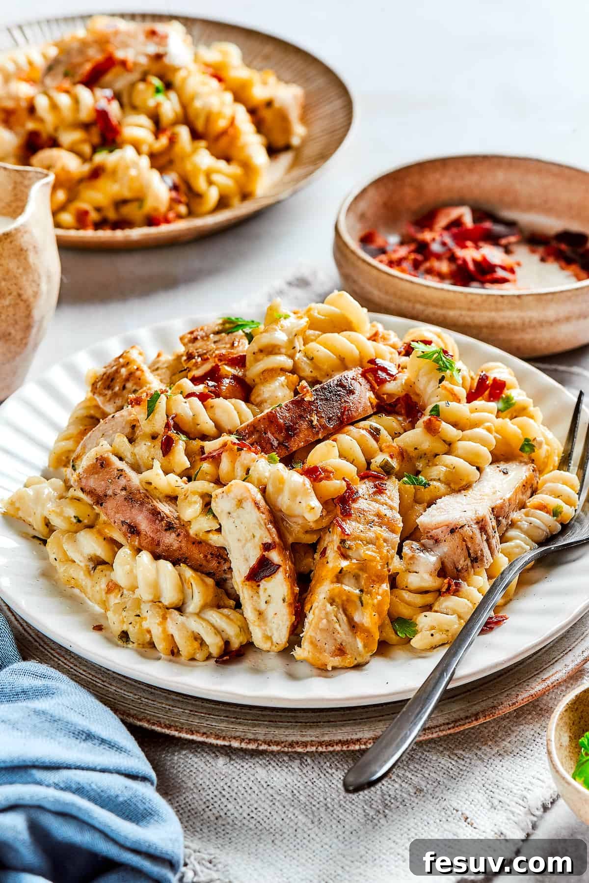 Savor the Richness of Chicken Bacon Ranch Pasta: A Family Favorite! Plates of creamy chicken bacon ranch pasta, garnished with fresh parsley, ready for a delicious meal.