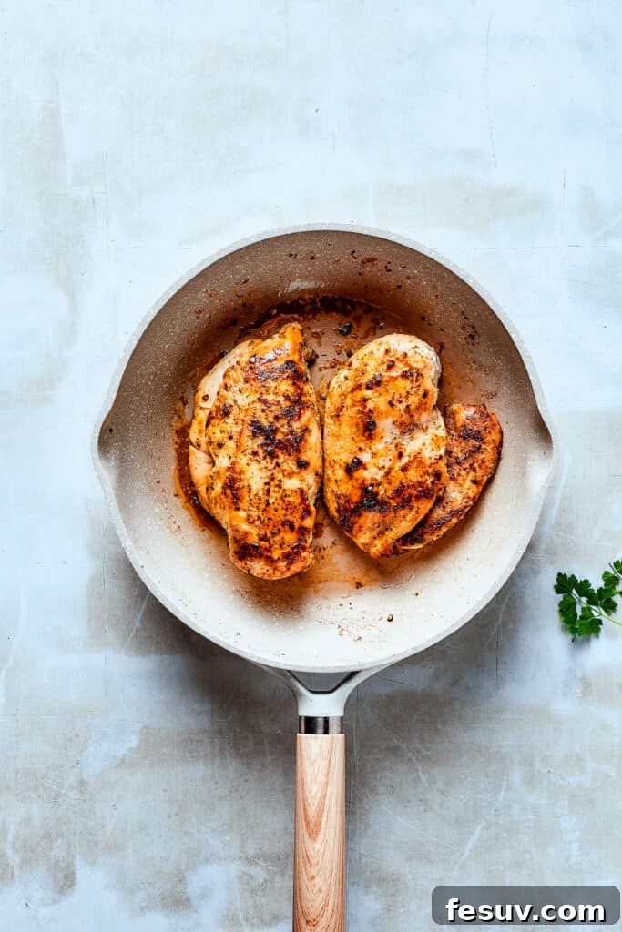 Searing Chicken for Chicken Bacon Ranch Pasta: Building Flavor! Cooking seasoned chicken breasts in a hot skillet with bacon fat.