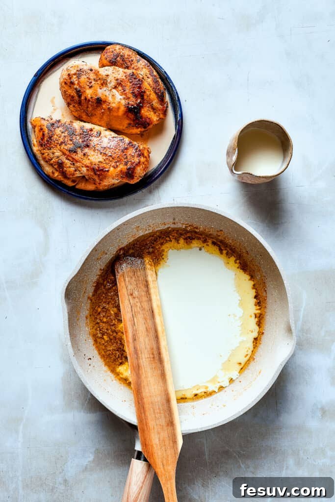 Achieving Perfect Creamy Sauce for Chicken Bacon Ranch Pasta! A wooden spoon stirring a creamy white sauce in a skillet, ensuring even consistency.