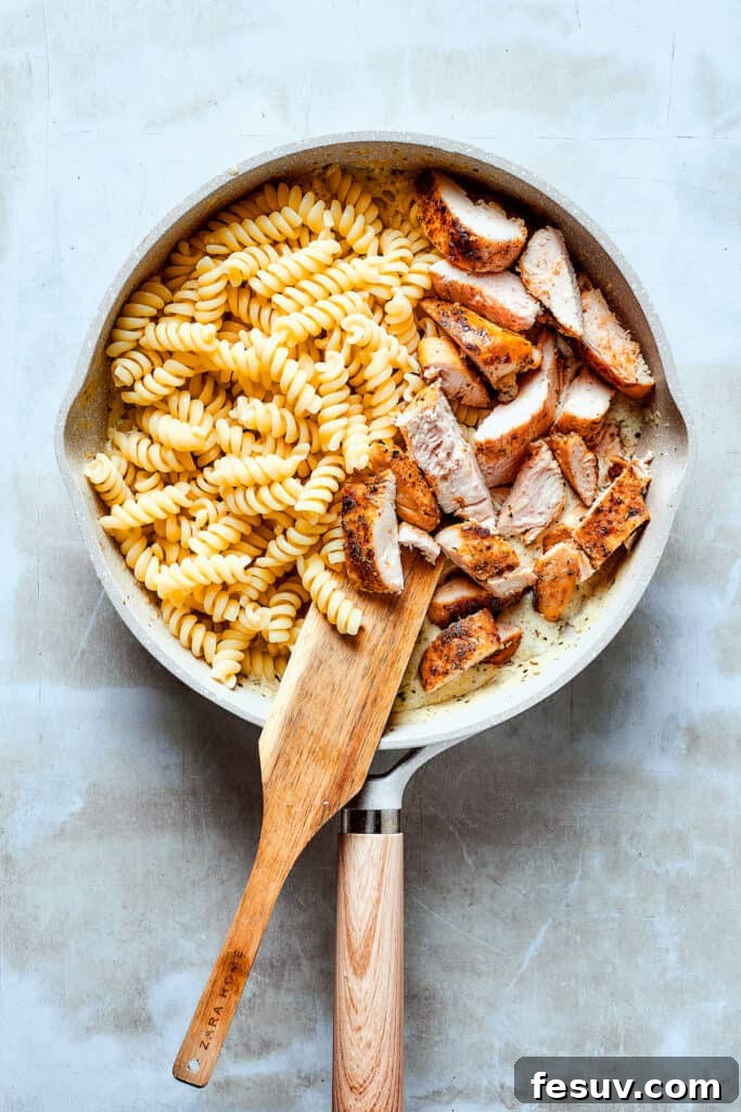 Combining Chicken and Pasta with the Luscious Ranch Sauce! Cooked chicken strips and al dente pasta being added to the creamy ranch sauce in a skillet.