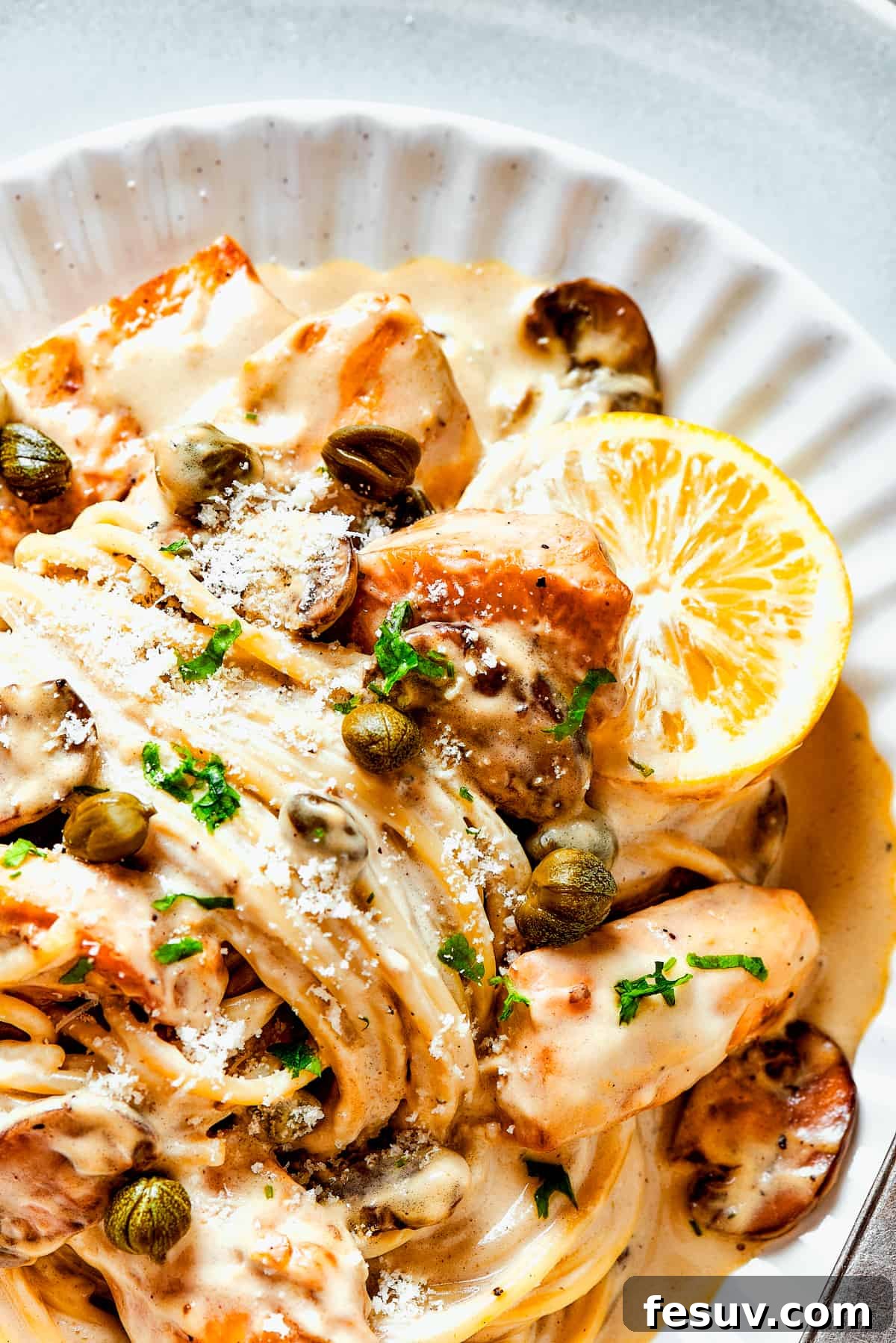 A chef's-kiss perfect plate of homemade chicken piccata. A beautifully plated dish of homemade chicken piccata with a rich, creamy sauce and a sprig of fresh herbs.