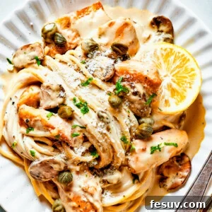 Cheesecake Factory-Style Chicken Piccata 2 Chicken in caper-lemon sauce with pasta on a pale dinner plate.
