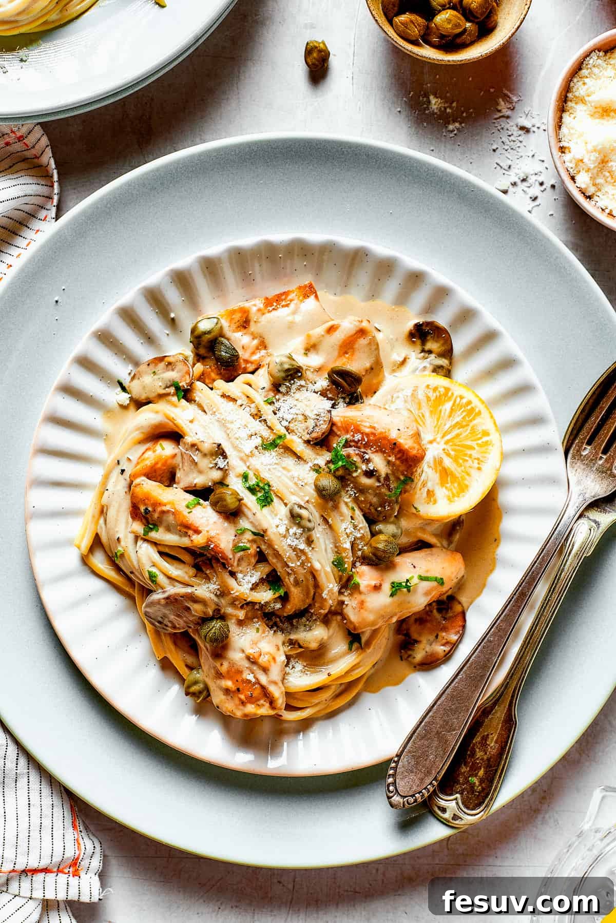Creamy pasta with chicken piccata, perfect for a cozy dinner. Close-up shot of creamy spaghetti in piccata sauce with succulent chicken slices, garnished with fresh parsley.