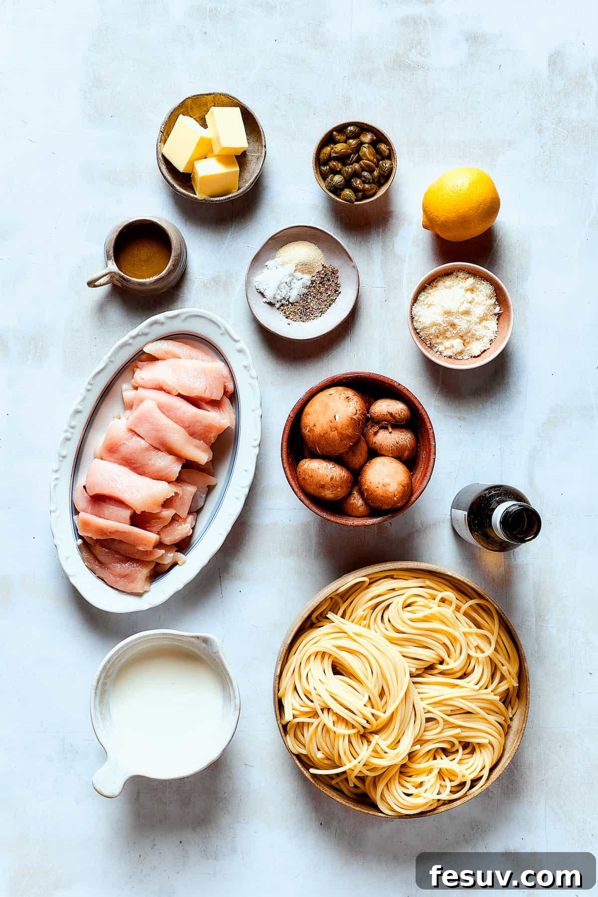 Fresh ingredients awaiting transformation into a delightful chicken piccata. All the fresh ingredients for Chicken Piccata Cheesecake Factory Copycat laid out on a clean work surface: chicken, mushrooms, lemons, capers, cream, parsley, butter, olive oil, and seasonings.