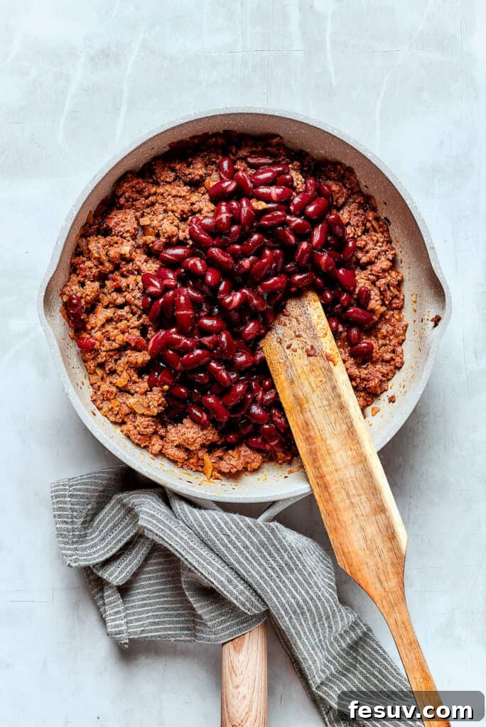 Adding beans to chili.