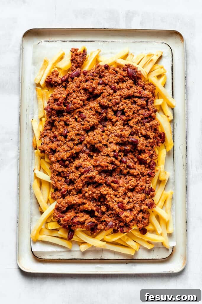 A baking sheet with french fries covered in chili.