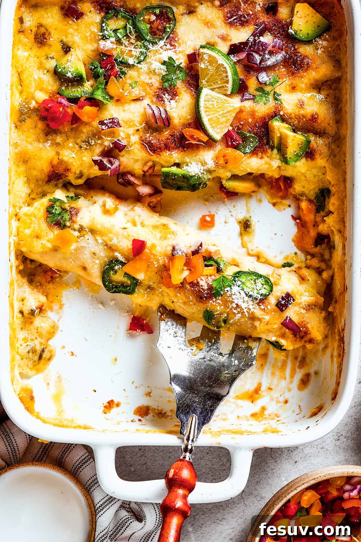 A serving fork resting in a dish of homemade enchiladas.