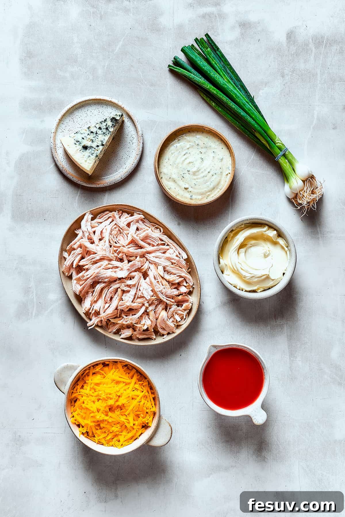 A beautiful arrangement of fresh ingredients for Crockpot Buffalo Chicken Dip on a rustic wooden table.