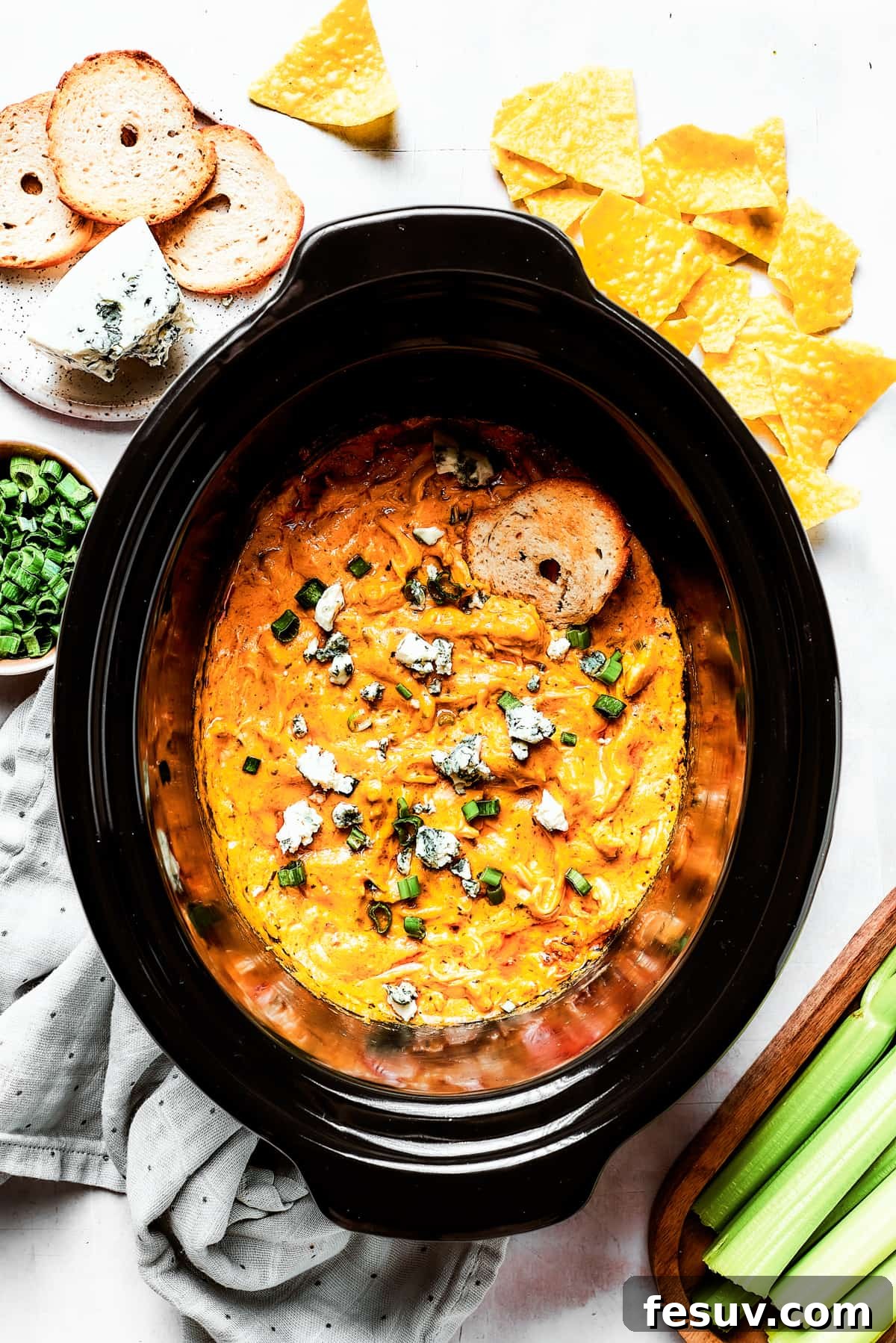 A slow cooker insert full of hot, cheesy, and bubbly Crockpot Buffalo Chicken Dip, ready to be served.