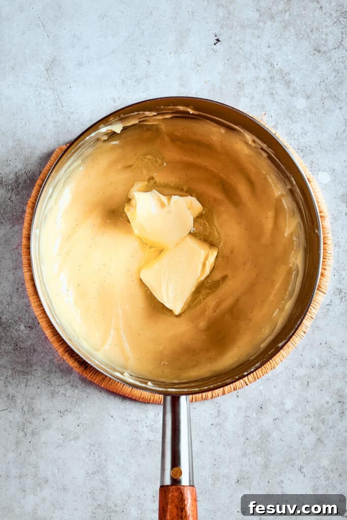 Butter adds gloss and flavor to the pudding. Stirring unsalted butter into warm banana pudding in a saucepan.