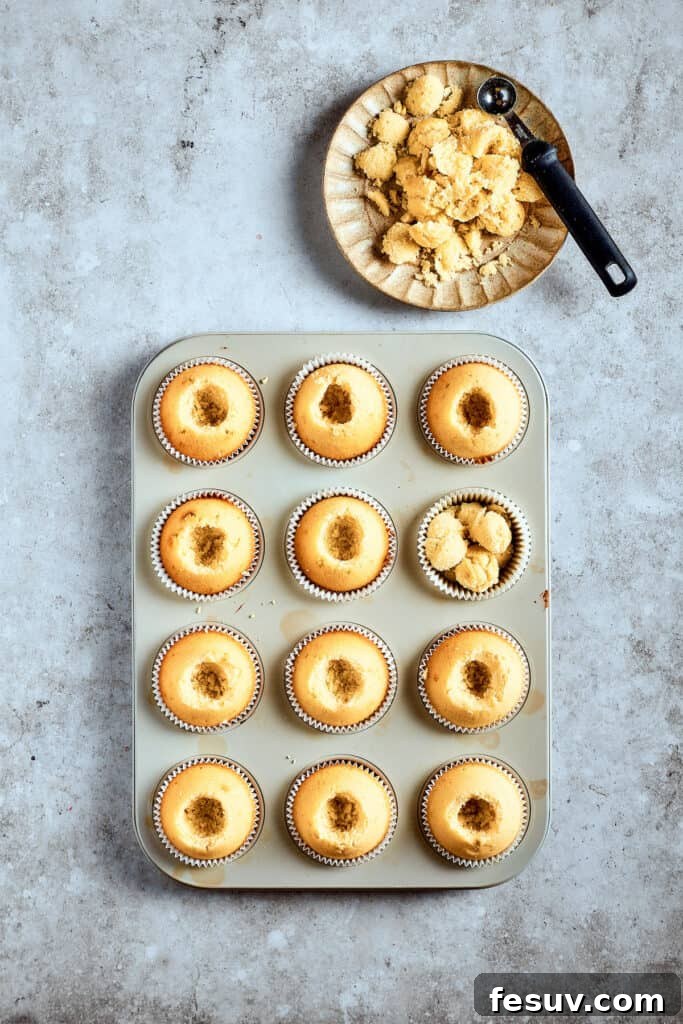 A cupcake corer makes quick work of preparing cavities. Cooled cupcakes in a cupcake pan, with their centers cored out, ready to be filled.