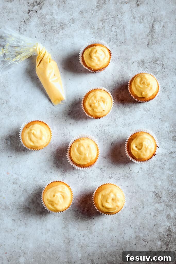 Overflowing pudding adds to the indulgence. Cupcakes filled and topped with a layer of creamy banana pudding, ready for whipped cream and garnishes.