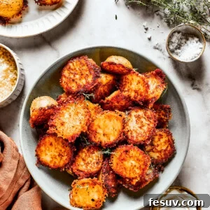 A bowl of baked potato halves crusted with parmesan cheese.