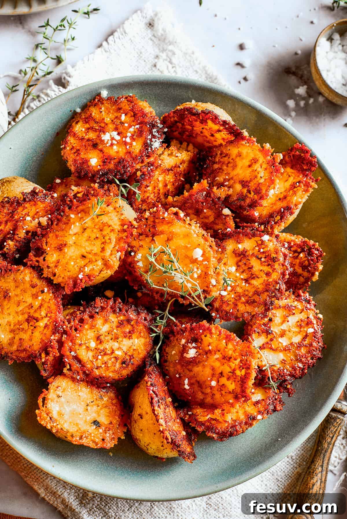 These tender potatoes with a crunchy, cheesy crust are the easiest, tastiest side dish you'll ever make. A viral TikTok recipe you'll love! Overhead image of parmesan-crusted potatoes in a bowl.