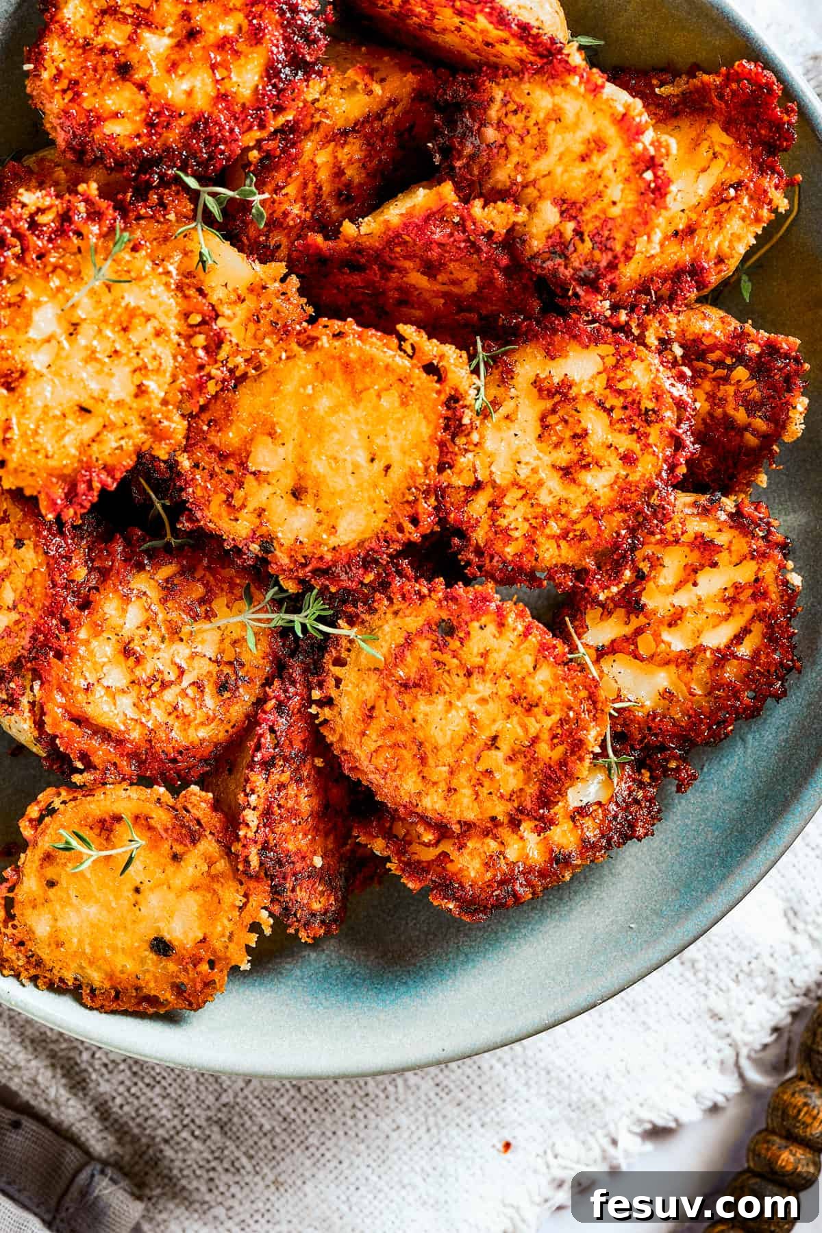 These tender potatoes with a crunchy, cheesy crust are the easiest, tastiest side dish you'll ever make. A viral TikTok recipe you'll love! Close-up of parmesan-crusted potatoes in a bowl.