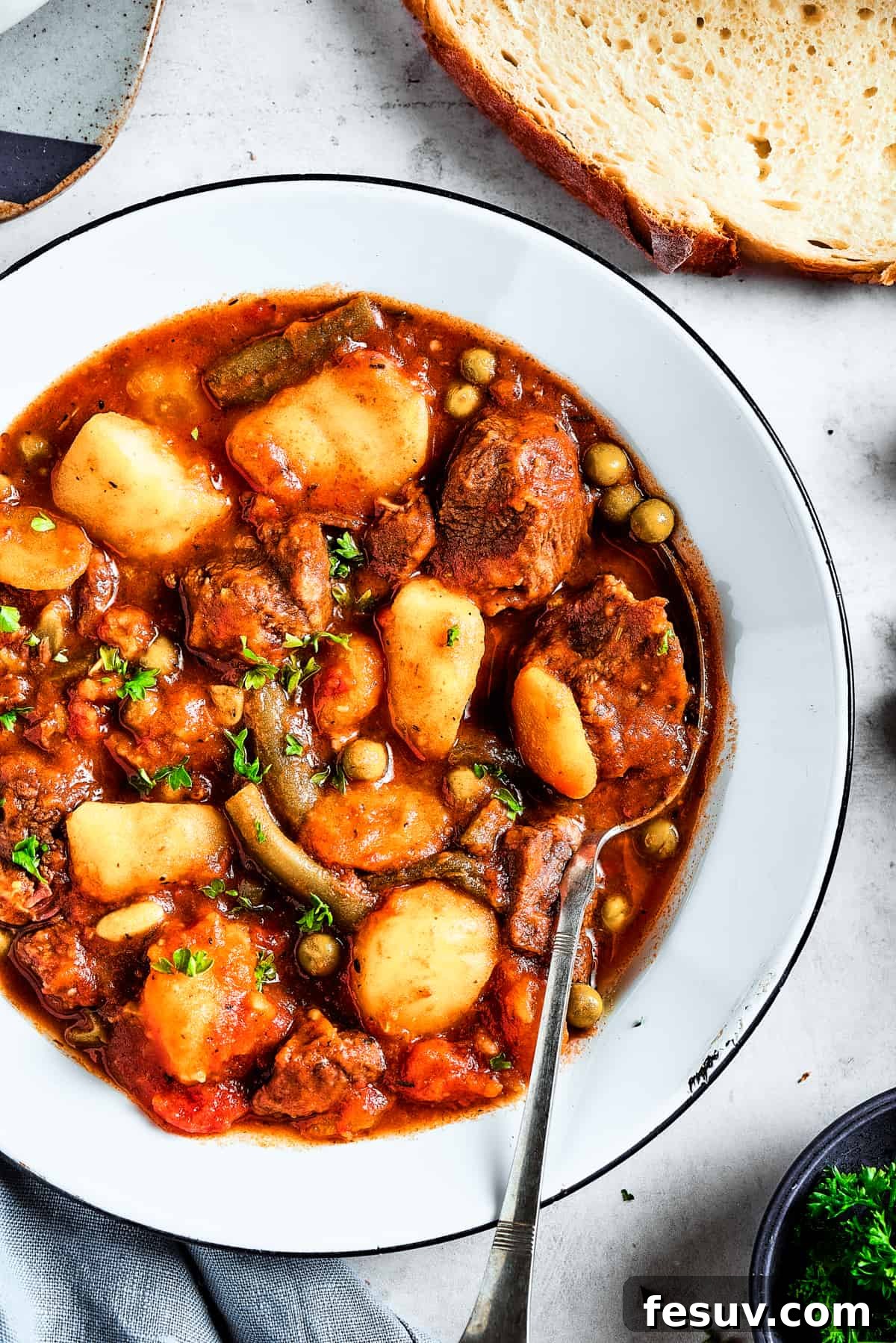 As the air gets crisper and the leaves turn golden, it's time to cozy up with a bowl of pure comfort - this old-fashioned Mulligan Stew! Overhead shot of a bowl with mulligan stew with mixed vegetables.